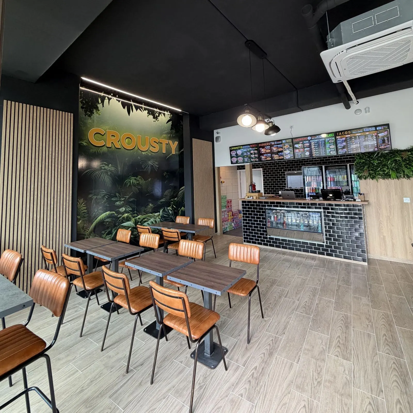 La salle de Crousty Naan : chaises en cuir camel, mur végétal Crousty et comptoir en carrelage noir